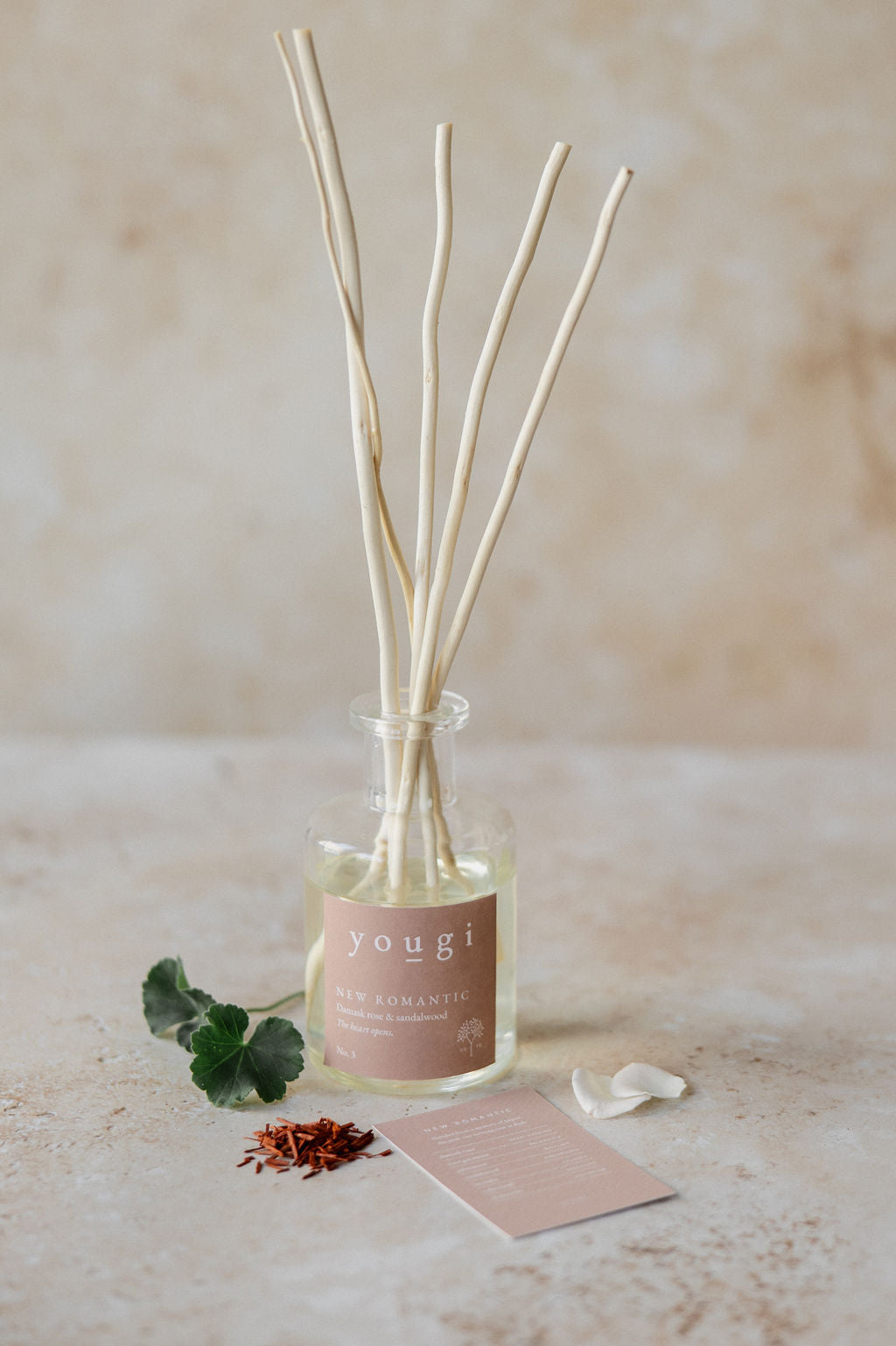 The New Romantic reed diffuser in frosted glass with rose petals and the scent card