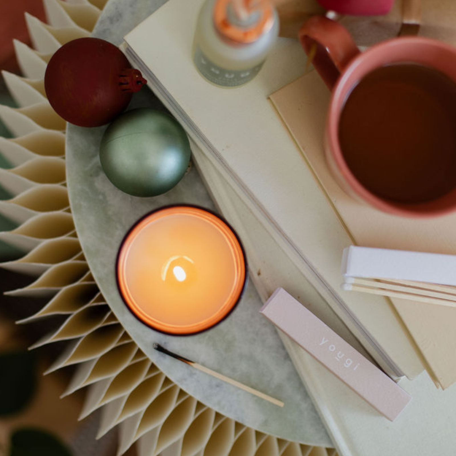 A stack of wellbeing books beside a lit candle.