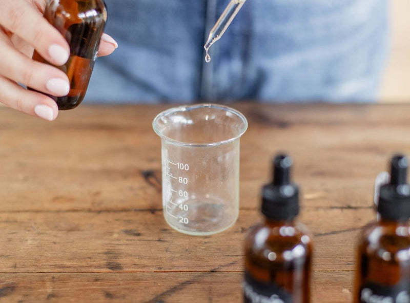 Measuring essential oil into a glass beaker at the Yougi studio