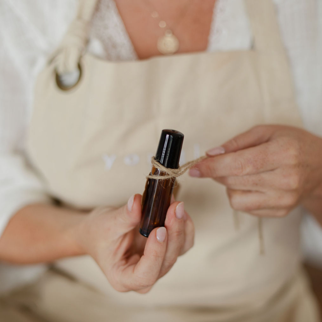 Hands tying twine on an amber perfume bottle