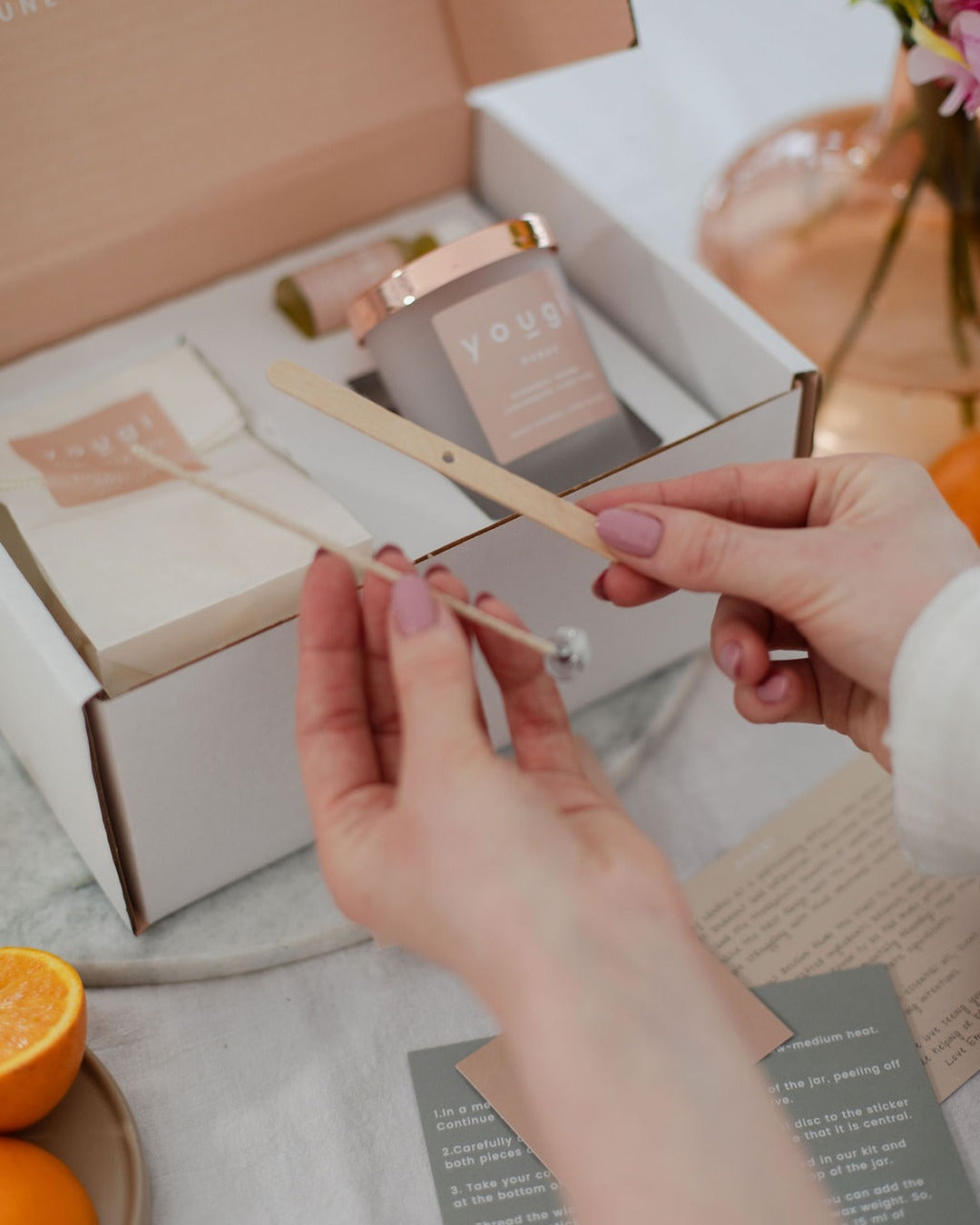 Threading the cotton wick, the candle-making kit open on the table