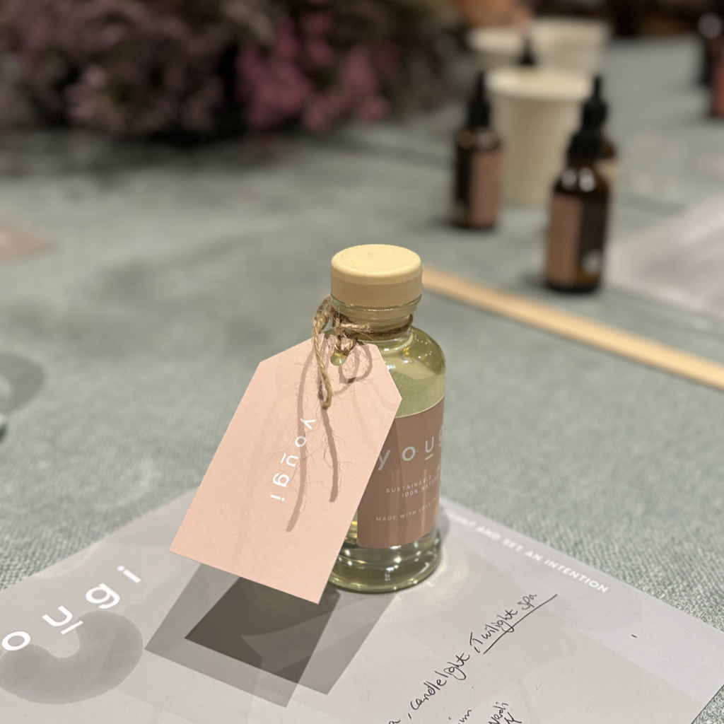 Small diffuser bottle with a wooden cap and pink label on a textured surface