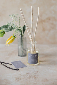 The Moonlight Bloom reed diffuser in frosted glass with yellow flowers and the scent card