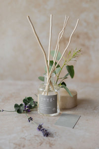 The Soothe reed diffuser with a sprig of eucalyptus and lavender on stone
