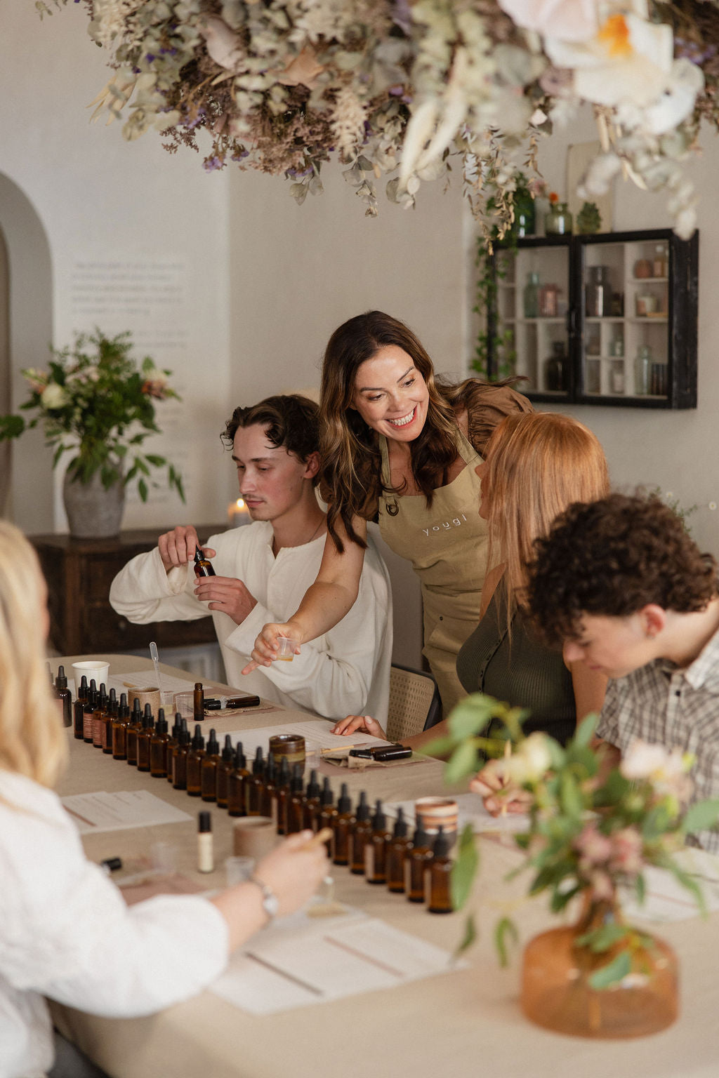 Emily and guests at the table under dried flowers at a Yougi workshop