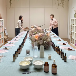 Two women standing at a long table with Yougi skincare products and flowers in the center.