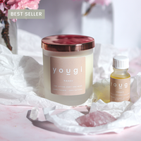 Happy candle in frosted glass with a pink label, beside its matching essential oil