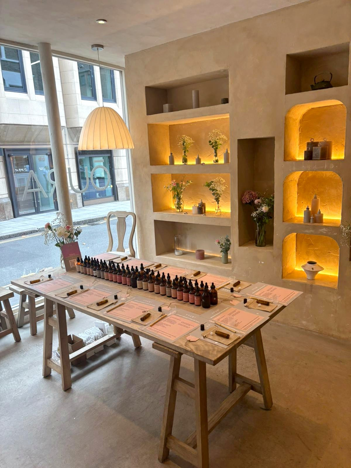 The Yougi studio set for the Oura Ring influencer event: trestle table laid with oils and placemats, lit shelves behind