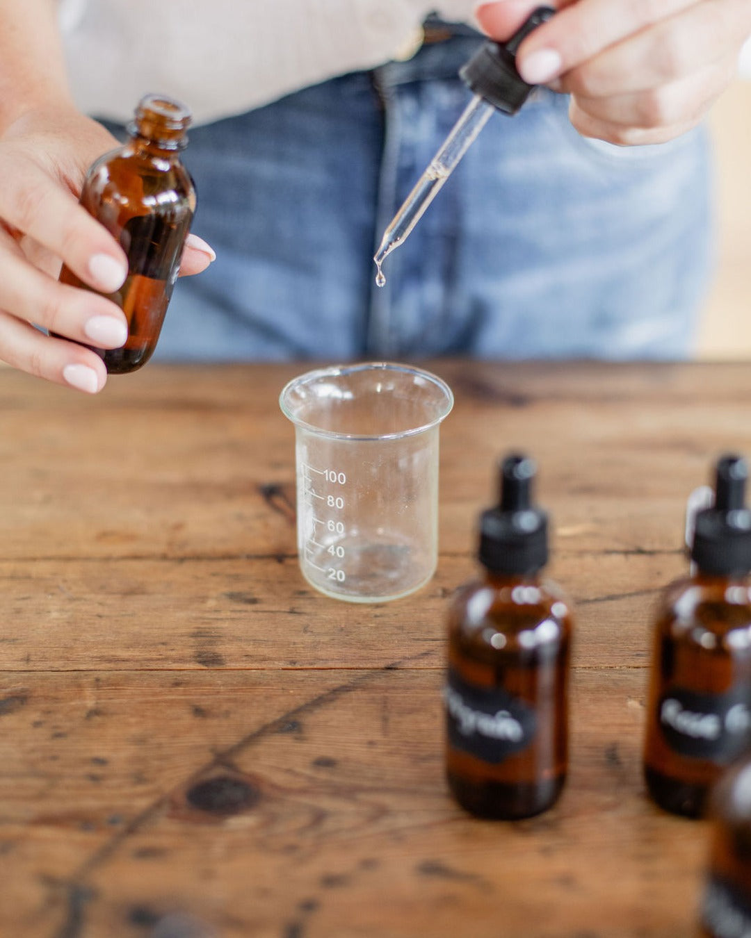 Measuring an essential oil blend with a dropper and beaker at the Yougi studio
