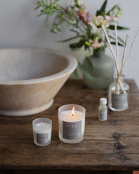 Soothe candles, regular and mini, on a wooden washstand with a stone basin, reed diffuser and garden flowers