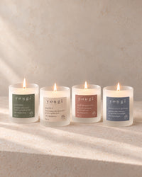 Soothe, Happy, New Romantic and Moonlight Bloom candles lit in a row, frosted white glass on stone