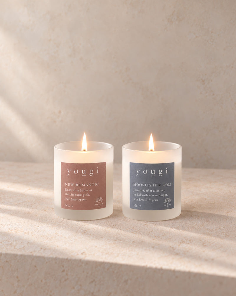 New Romantic and Moonlight Bloom candles lit side by side in frosted white glass, on stone